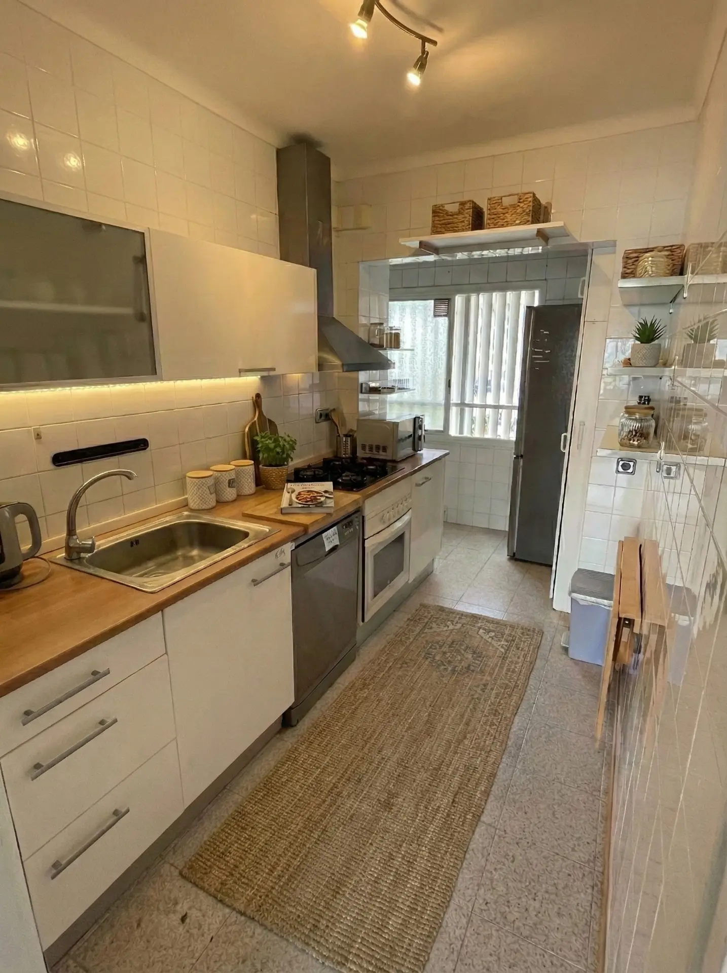 The kitchen with dishwasher, oven, gas hob and full fridge
